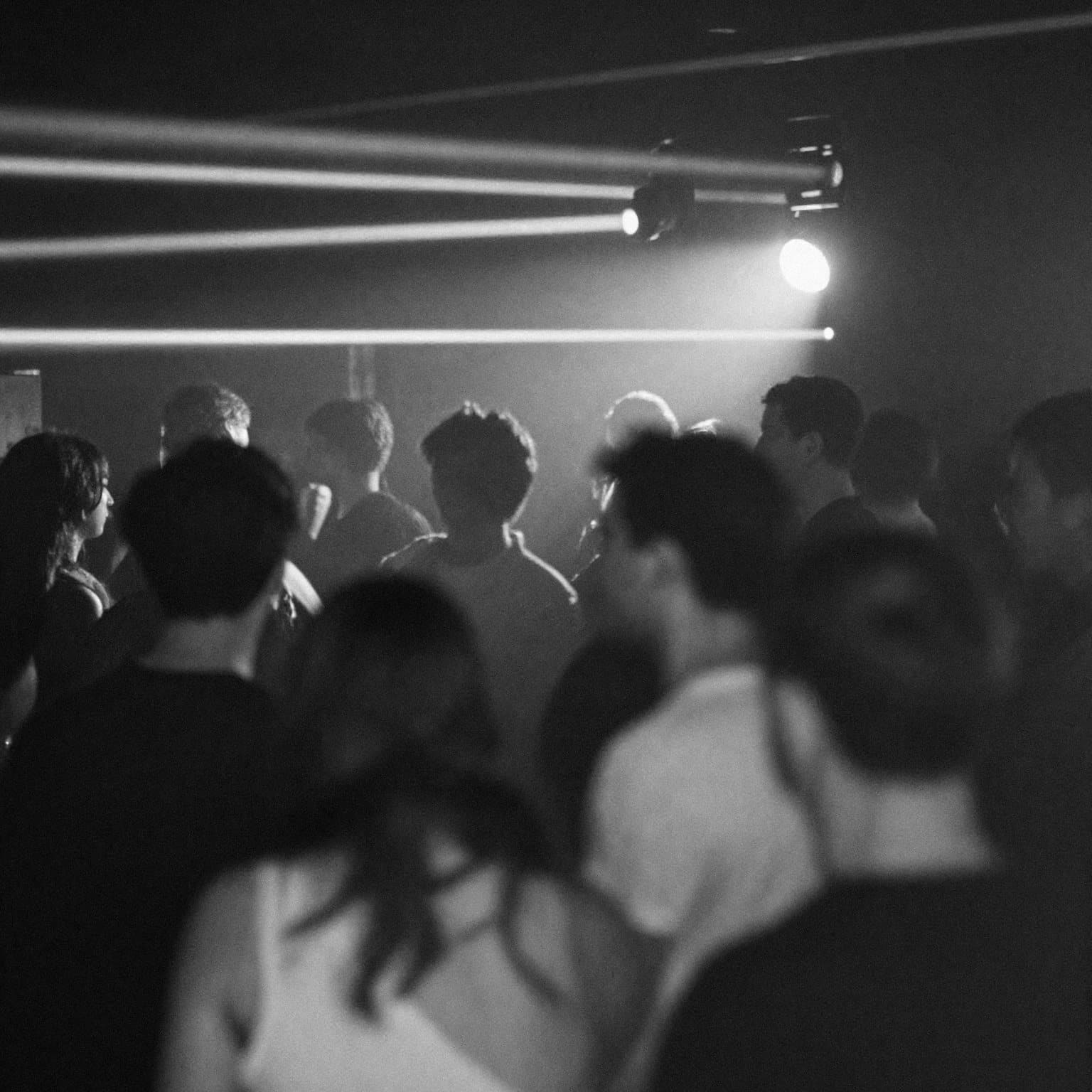 A crowd dancing under white light beams at a night party
